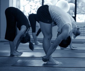 Students in forward fold practicing yoga at studio